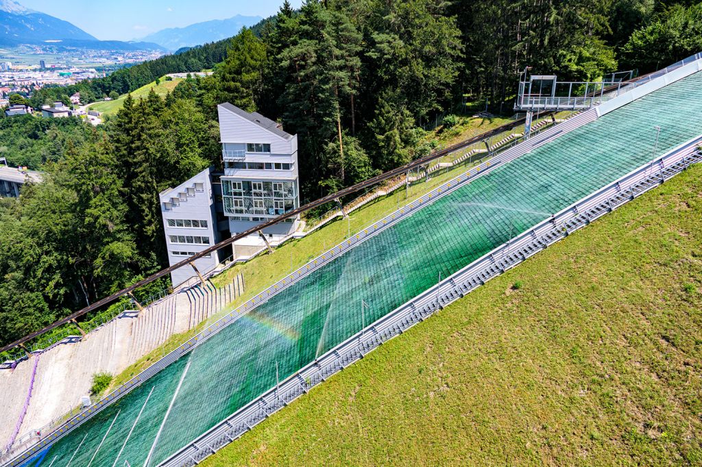 Punktzahl: 20 - So sieht der Aufsprunghang aus. Die Mattenschanze ist ganzjährig nutzbar. Die Matten müssen -wie hier mit Regenbogen zu sehen- regelmäßig bewässert werden.  - © alpintreff.de - Christian Schön